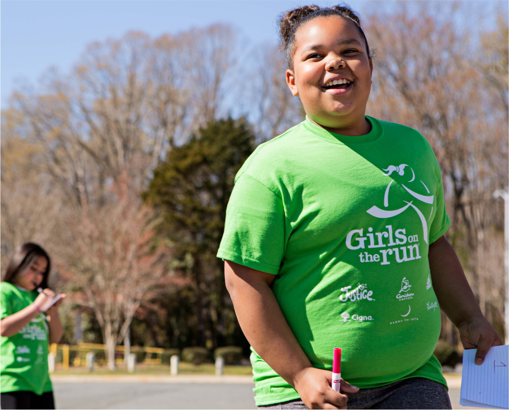 A Girls on the Run participant smiles while outside at program practice
