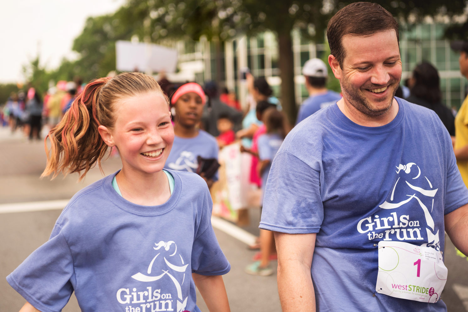 Girls on the Run participant and coach smile while running at 5K celebration