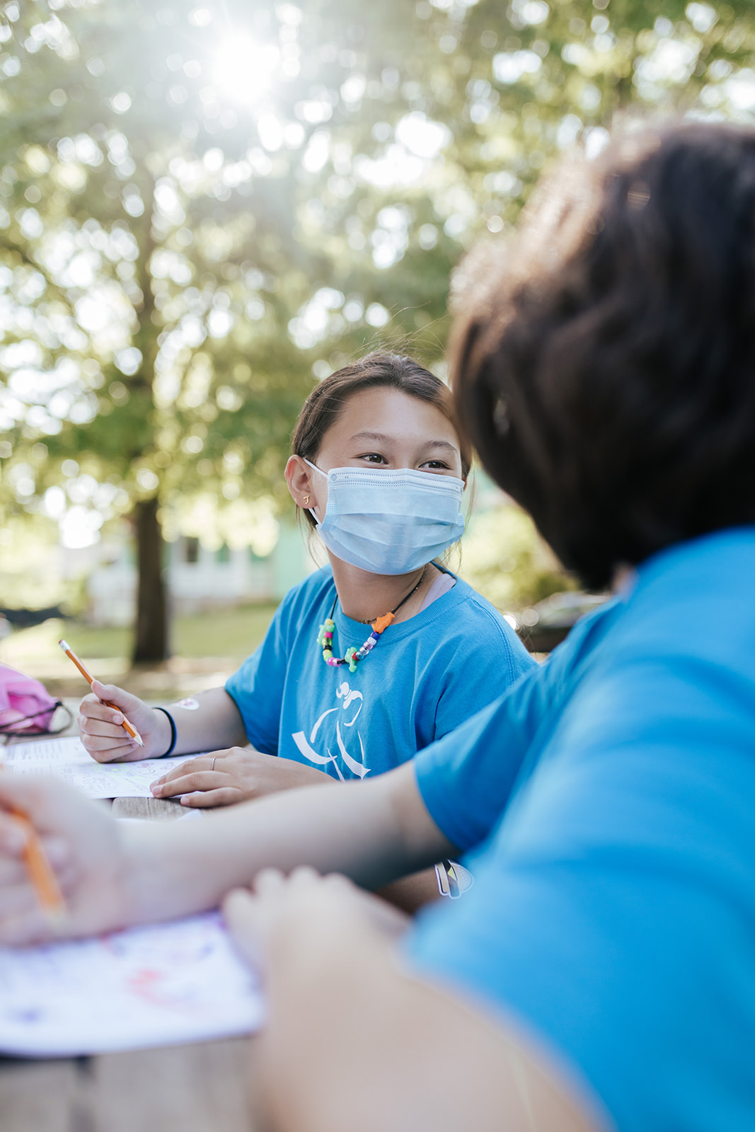 Girls on the Run participant smiles outside while wearing mask and working in her journal